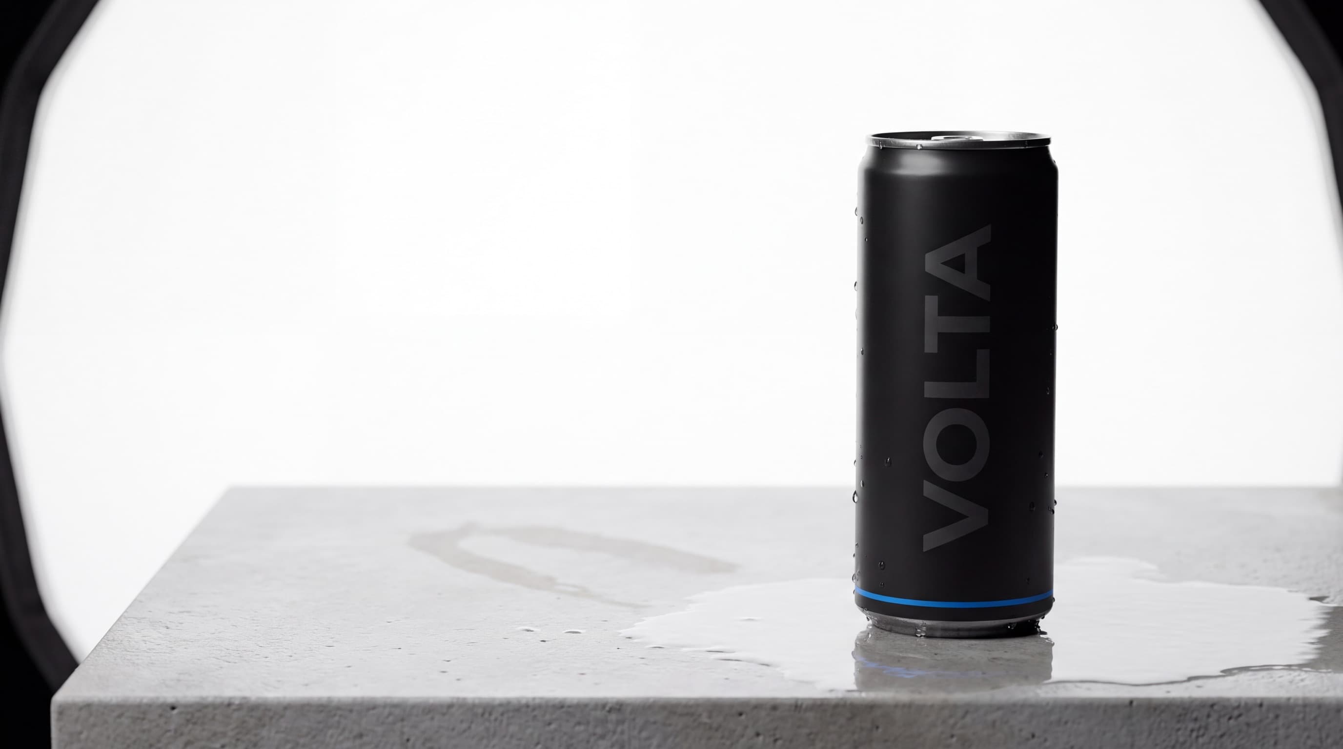 Matte black VOLTA energy can on wet concrete under studio light