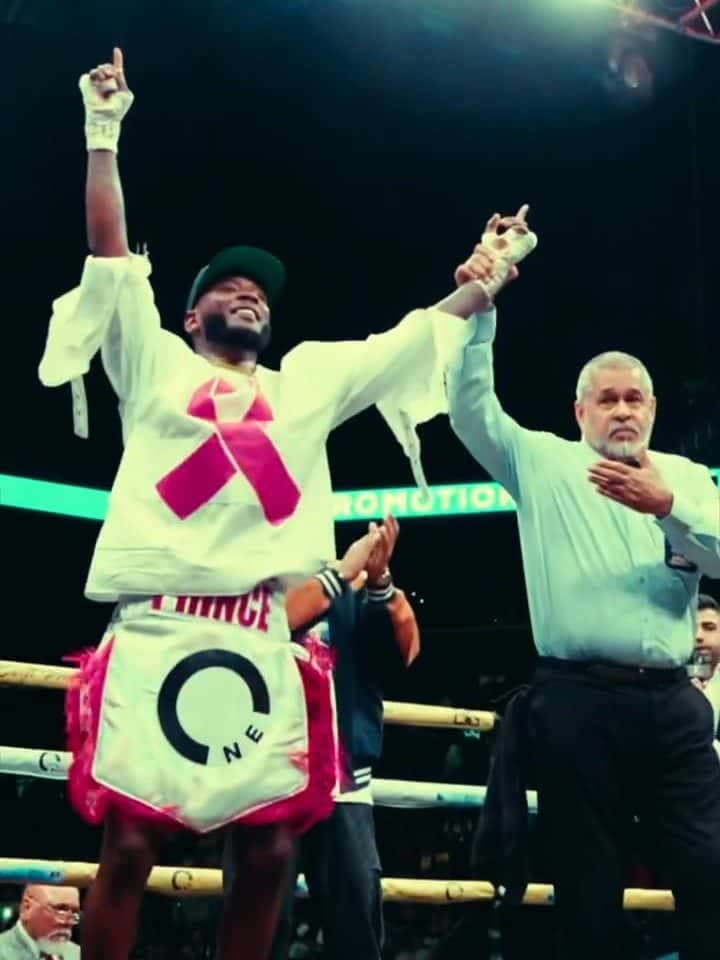 A fighter in One Water trunks raising his arms after a win at fight night