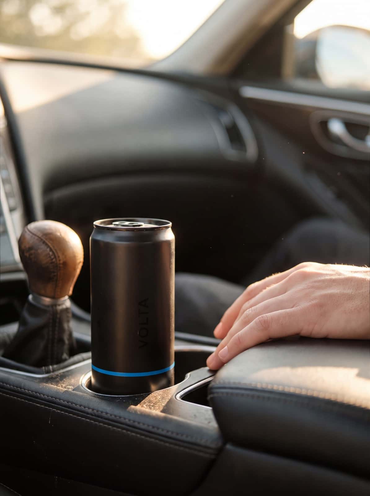 VOLTA can in a car cup holder beside the driver's hand on the armrest