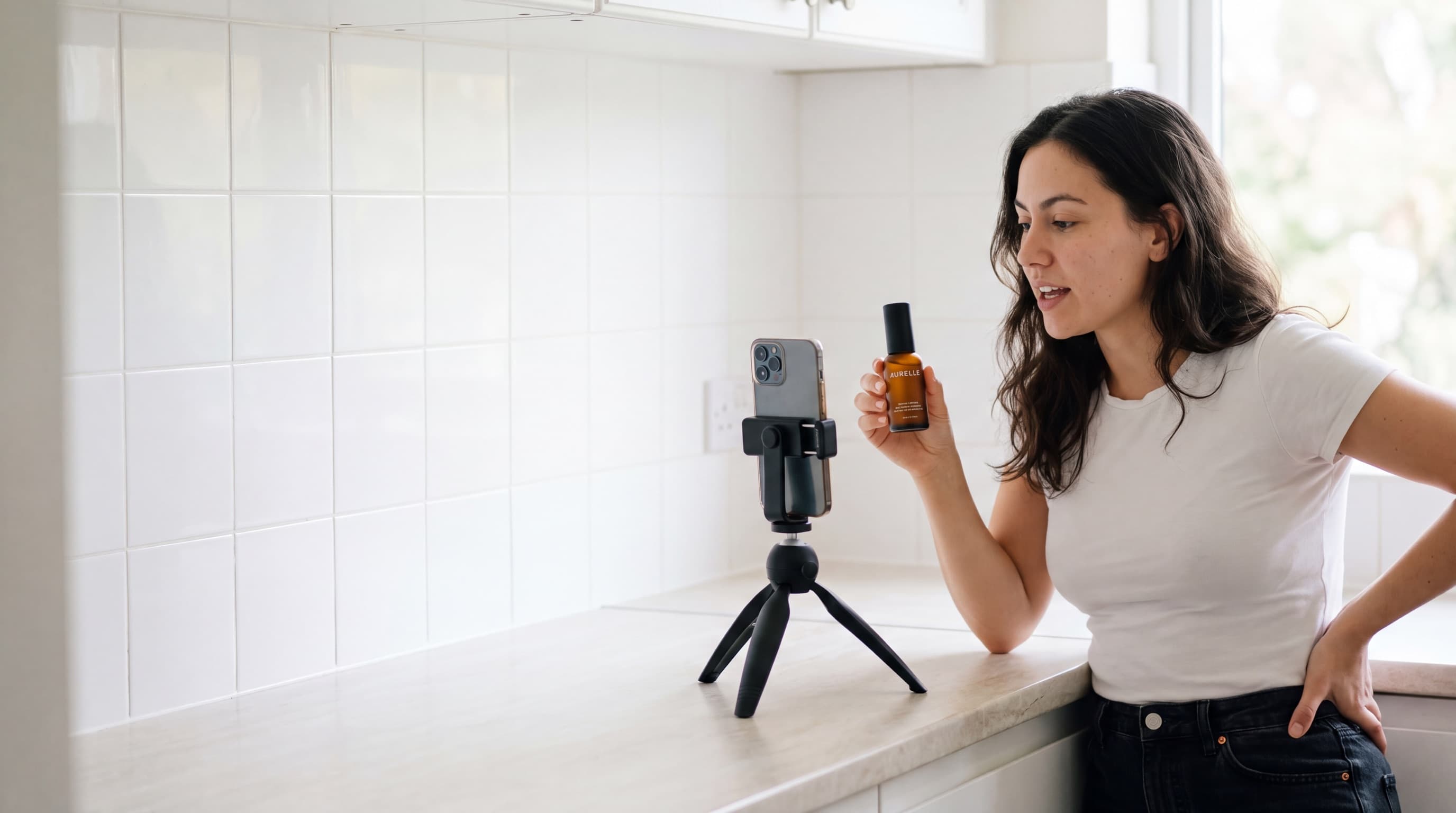 Creator recording herself at a kitchen counter holding an AURELLE serum